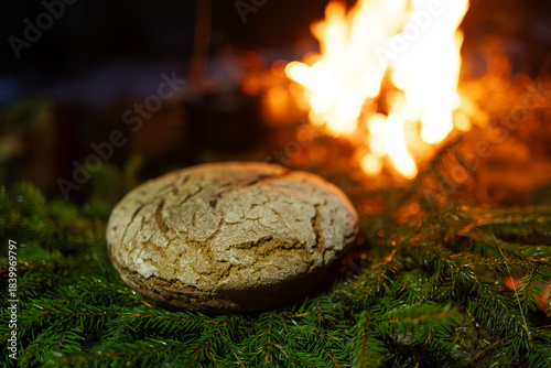 Homemade round bread against the backdrop of a bonfire
