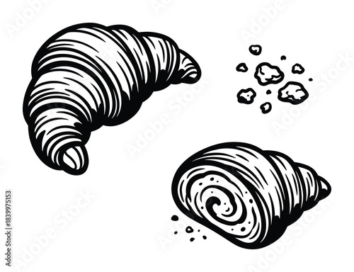 Freshly baked croissants, one whole and one cut, with crumbs. Delicious pastry perfect for breakfast.