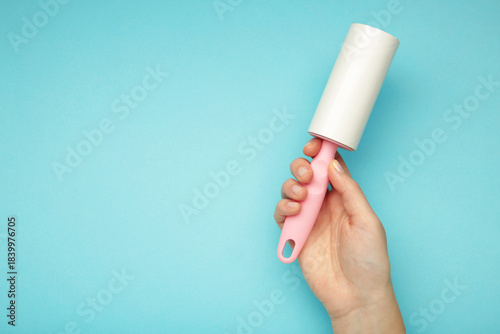 Woman holding lint roller on blue background. Top view