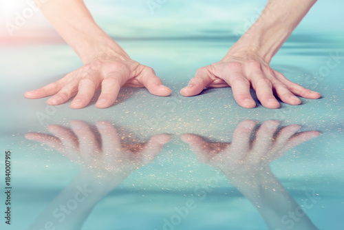 Hands touching reflective water surface with sparkles creating contemplative calm mood