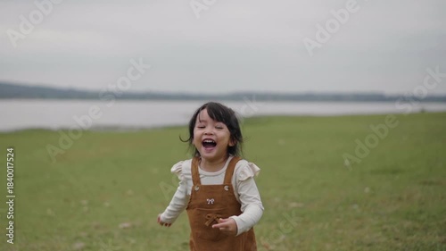 slow motion of toddler girl walking on a grass field near the river