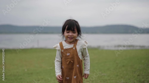 slow motion of toddler girl walking on a grass field near the river