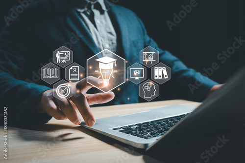 Business professional using a laptop with virtual education and innovation icons, representing digital learning, online training, knowledge management, and modern technology for corporate growth.