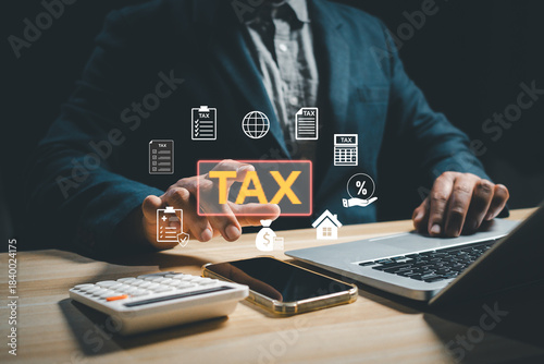 Businessman calculating digital tax using laptop, calculator, and smartphone with virtual tax icons, representing finance management, accounting, taxation system, and online financial compliance.