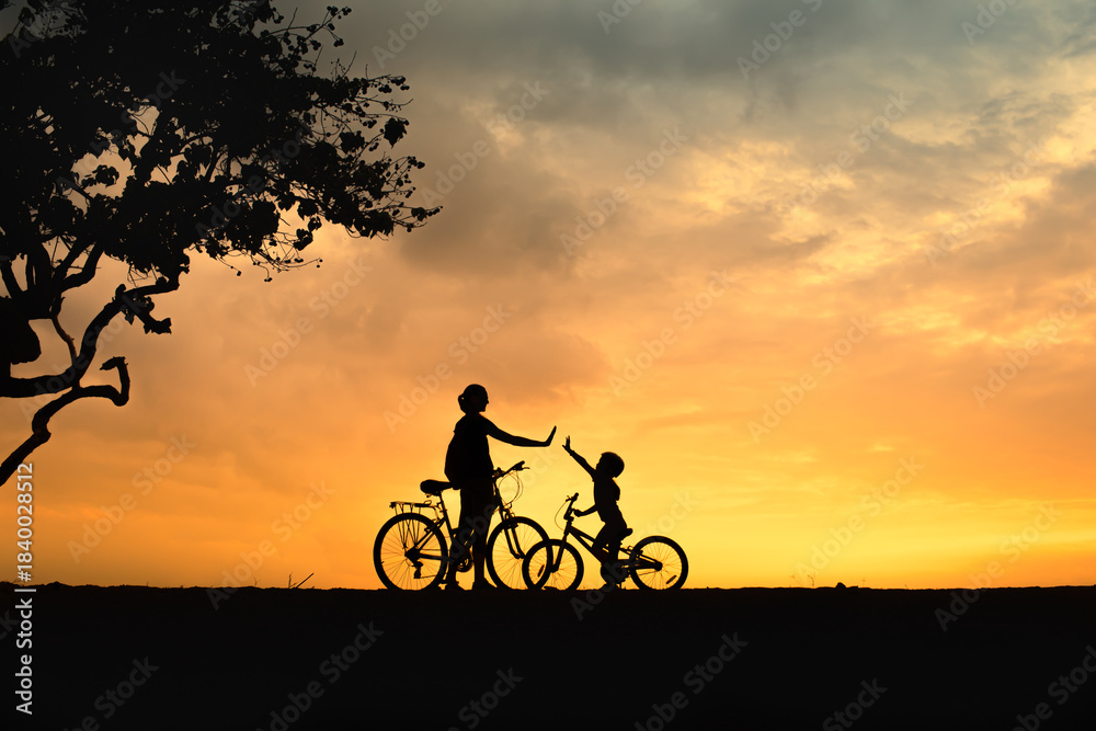 Fototapeta premium Mother and child biking at sunset – silhouette of family high-fiving outdoors, active lifestyle parenting