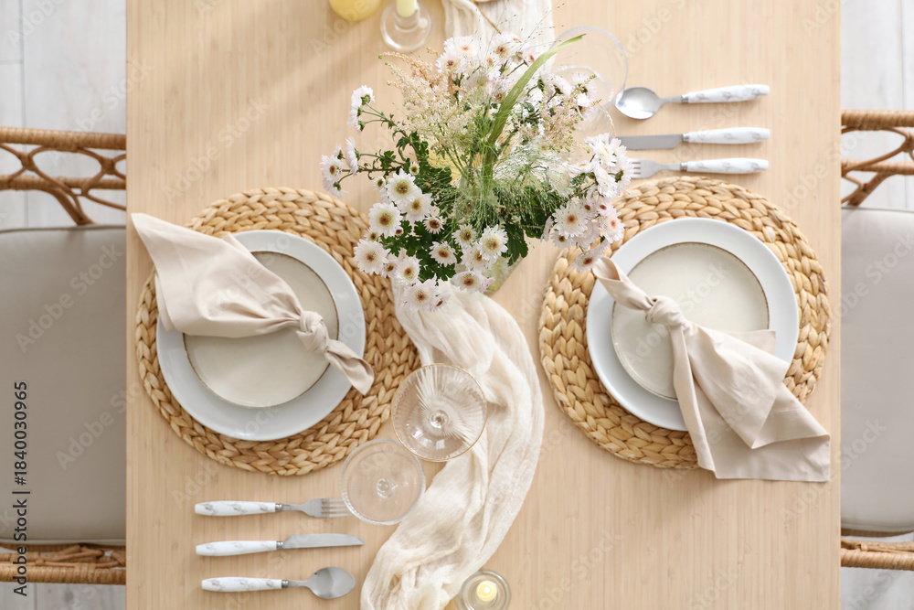 Fototapeta premium Beautiful table setting with bouquet of flowers and candles in light dining room