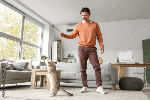 Young man playing with cute...