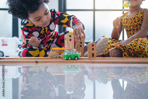 Boy and a girl, dressed in African traditional clothing, are playing together with toy cars on the floor. with copy space