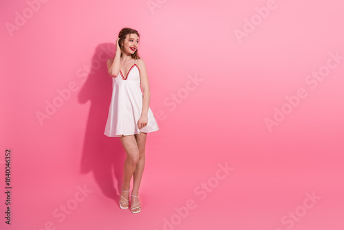 Фотография Young woman wearing a short white dress in front of a pink background posing wit