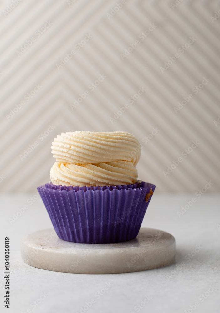 Φωτογραφία Close-up of a vanilla cupcake in a purple wrapper topped with swirled buttercrea