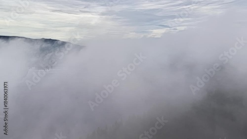 dense fog rolling over mountain ridges, drone surveyor mapping timbered slopes while hiker silhouette fades