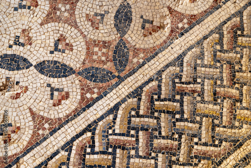 Close view of an ancient floor mosaic with weathered tesserae forming geometric diamond motifs, ideal for archaeology themes, art history contexts, texture uses and Mediterranean heritage 