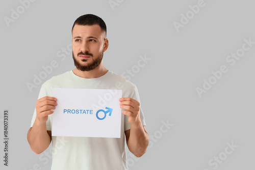 Young man holding paper wit...