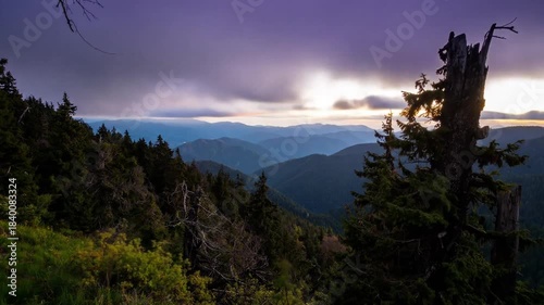 A scenic vista reveals mountain ranges under a dramatic purple and orange-hued sky