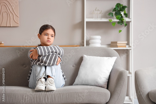 Sad girl sitting on sofa at...