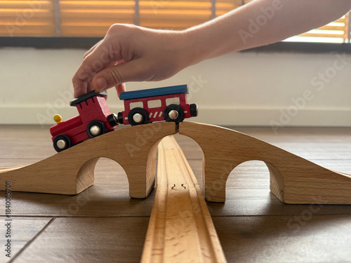 hand pushing wooden train on bridge and track on wooden floor concept of toy stores, education, children