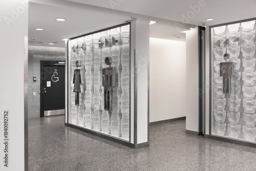 Modern public restroom entrance with metal gender signs and accessible toilet door in a clean hallway.