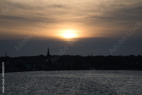 Sunset over the sea with boat trail and silhouette on the horizon
