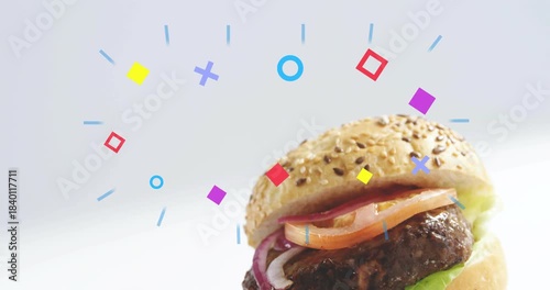 Sesame burger sliding up from lower right revealing layers while vivid shapes orbit promoting brand