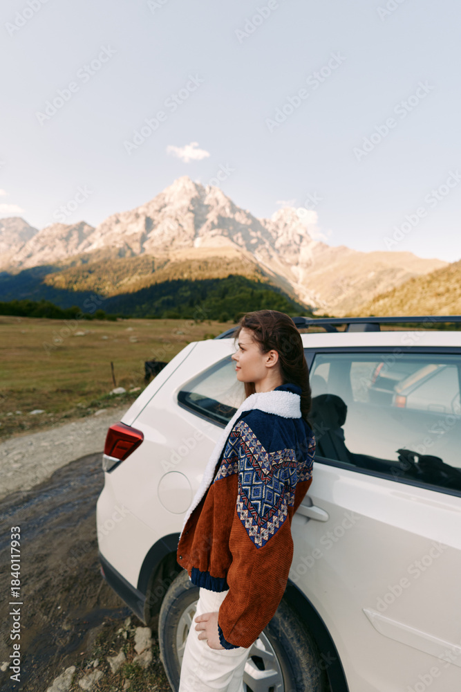 Naklejka premium Woman leaning against white car with cozy sweater in mountain landscape, outdoor travel and roadtrip portrait capturing scenic autumn adventure, peaceful nature and quiet exploration outdoors.