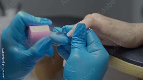 A manicurist is applying gel polish to a customer's nails in a manicure salon.