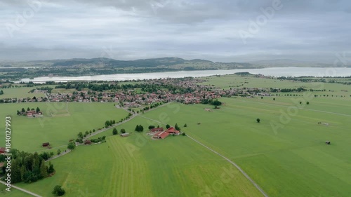 Aerial view from drone flying over village houses towards the castle on hill above summer field near Neuschwanstein Castle in Germany, Europe. High quality footage in 4k format