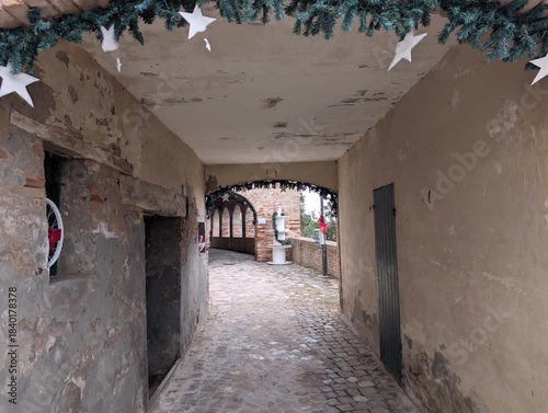 Arco in mattoni con una decorazione natalizia sopra, costituita da una ghirlanda con stelle.  Via lastricata con pavimento in ciottoli, nell'antico borgo medievale di Serraungarina