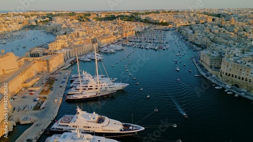 Aerial view of luxury yachts and sailboats in a crowded marina, Malta. Top down drone shot of turquoise Mediterranean water and summer nautical lifestyle.
