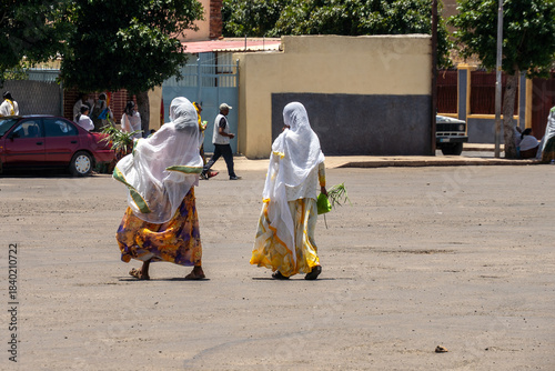 Schilderij op canvas Women with white scarves and yellow dresses walking in Asmara, Eritrea