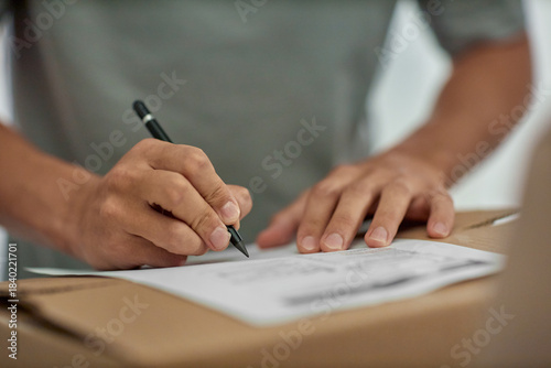 Photography Man signing document on cardboard box, closeup of hands holding pen and writing,