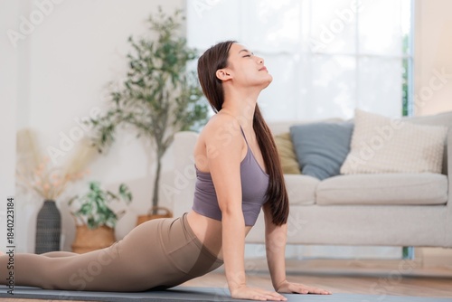 Woman practices yoga in a bright room with plants and a couch in the background during the day Free Download Woman practices yoga in a bright room with plants and a couch in the background during the day - GFXLoad
