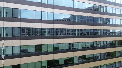 Aerial view of modern office building exterior, showcasing reflective glass windows and architectural design, with a smooth camera zoom in emphasizing the structure's details
