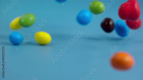 Falling colorful chocolate candies on a pastel background, super slow motion 1000 fps