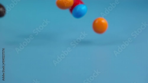 Falling colorful chocolate candies on a pastel background, super slow motion 1000 fps