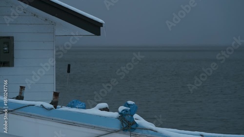 岸辺に陸揚げされた小さな漁船のある雪景色