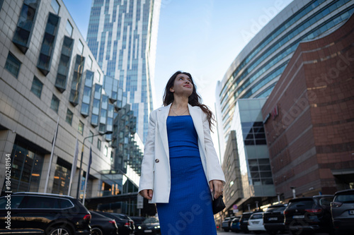 Принти на полотні A young ambitious girl walks the streets among the skyscrapers and cars in a big city