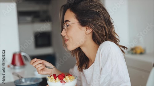 Woman enjoys eating her healthy fruit breakfast in the kitchen.