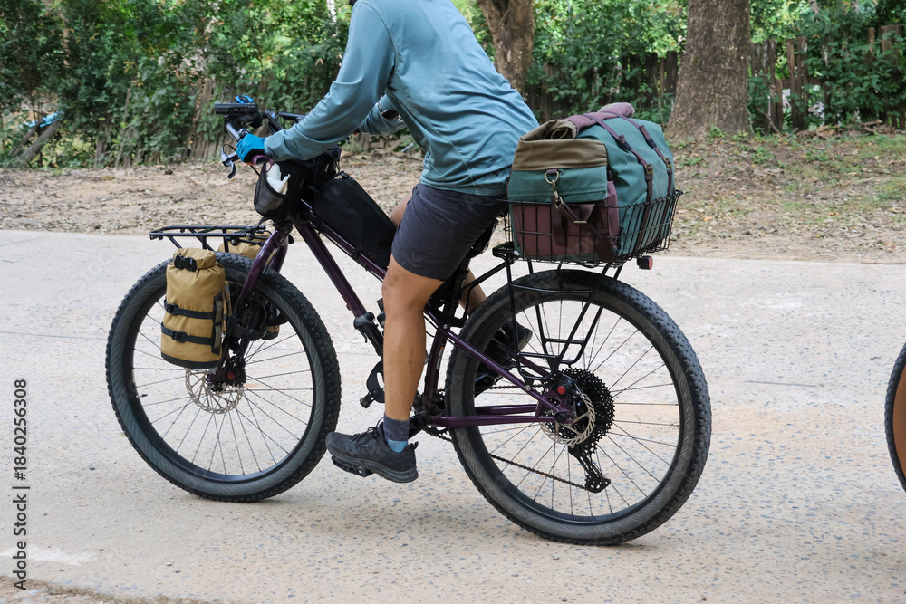 Obraz premium Cyclist on bikepacking adventure tour, riding bicycle with luggage and gear. Person enjoying freedom of an outdoor travel journey on an active holiday expedition