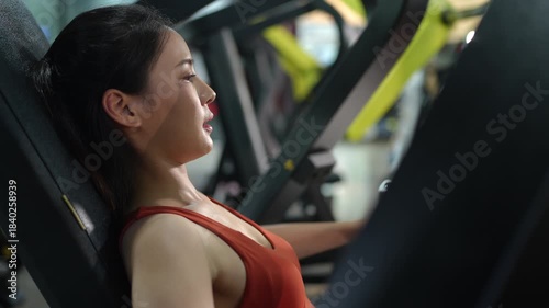 Asian woman working out on gym equipment to improve fitness, strength, and health. Ideal for concepts of healthy lifestyle, exercise routine, wellness, self care, and modern indoor fitness training