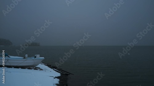 岸辺に陸揚げされた小さな漁船のある雪景色