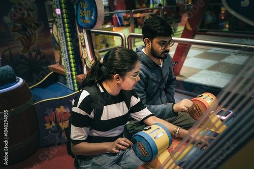 Friends enjoying arcade games together at a brightly lit indoor gaming zone.