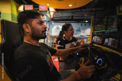 friends enjoying a car racing arcade game at a brightly lit indoor gaming zone.