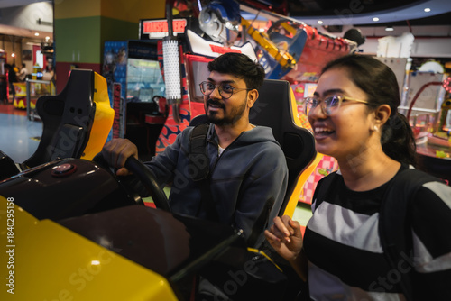 friends enjoying a car racing arcade game at a brightly lit indoor gaming zone.