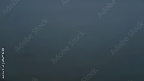 ブルーグレイの水面を背景に降る雪