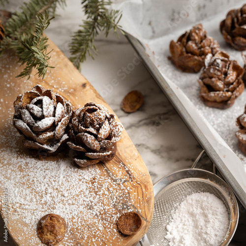 Individual, pinecone desserts made of brownies and whipped cream cheese sprinkled with powdered sugar for a festive forest nature theme.  Two on a wooden board, close-up.