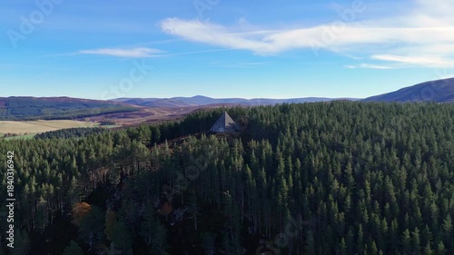 Aerial view of a pyramid situated in dense lush forest perched on a hill.