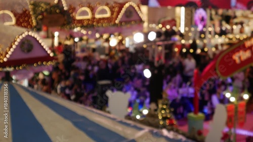Abstract blurred background of a festive indoor holiday event or Christmas market with colorful bokeh lights, red stairs and crowds.