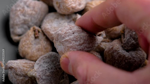 Hand picking a dried fig dusted with powdered sugar close up
