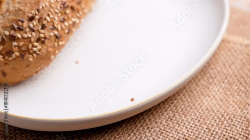 Hand picks up a fresh bread baguette with sesame and flax seeds
