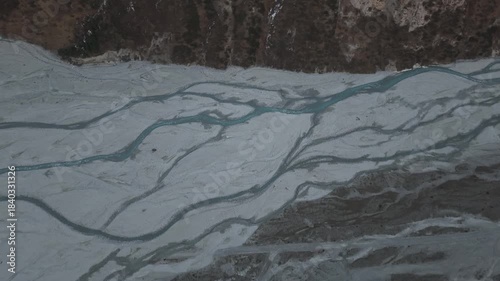 Aerial view captures the winding river flowing through rocky terrain, showcasing the intricate patterns of the landscape, camera pans smoothly to reveal the continuous flow of water